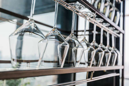 Wine glasses hang up side down on the steel rack. Ready for use.