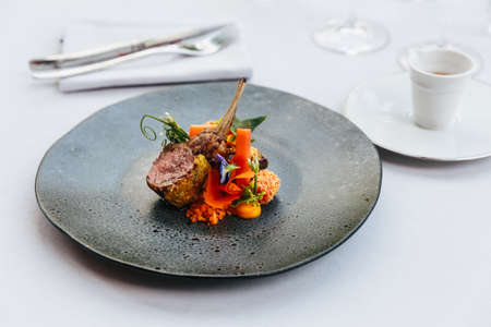 Modern French cuisine: Roasted Lamb neck & rack served with carrot, yellow curry served in black stone plate.の写真素材
