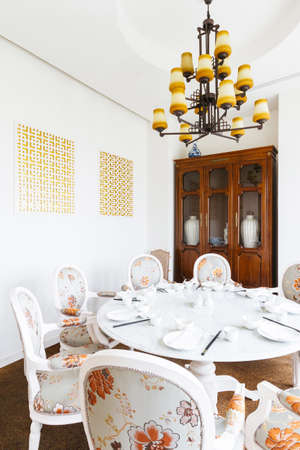 Modern Chinese restaurant VIP room with flowers on fabric decorated on chairs. wooden cabinet with porcelains inside and chandelier.の写真素材