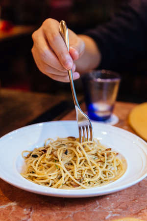 Mushroom and Garlic Spaghetti with a fork held by a hand.の写真素材