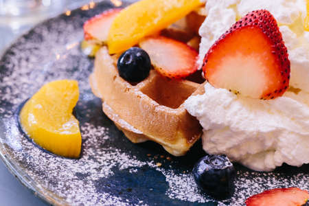 Close up Fresh baked Pancakes topping with strawberry, orange, blueberry and whip cream.の写真素材