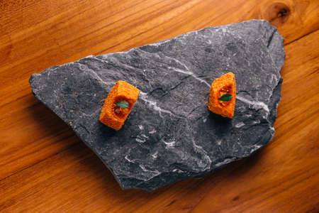 Creative Fine Dinning: Fish with orange colour glaze topping with ikura served on stone plate.