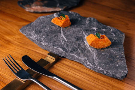Creative Fine Dinning: Fish with orange colour glaze topping with ikura served on stone plate.の写真素材