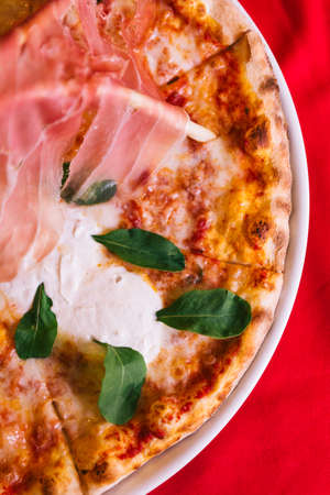 Top view of Neapolitan Pizza made with tomatoes and mozzarella cheese and topping with Parma ham bridge.の写真素材