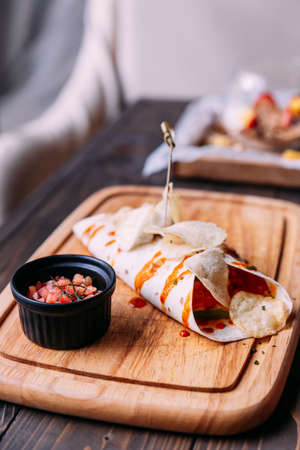Meat kebab with chips topping with sauce and served with tomato salad on wooden plate.の写真素材