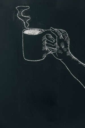 Chalk hand drawing a hand holding coffee cup with steam on black board near top of the frame.の写真素材