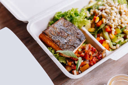Clean food meal box: Grilled salmon fillet with tomato and bean sprout salad including carrot and corn.の写真素材