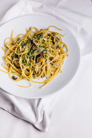 Top view of Oyster spaghetti served in white plate on white tablecloth.の写真素材