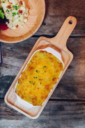 Hot baked lasagne with cheese melting surface served in wooden plate.