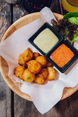 Fried Mozzarella Cheese Balls served with mayonnaise and thousand island sauce in wooden bowl.の写真素材
