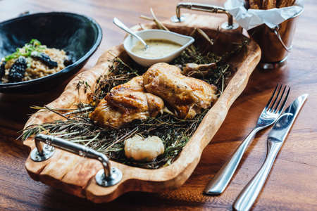 Roasted chicken with herbs, rosemary and garlic in wooden tray served with white sauce and peeled potato fries.の写真素材