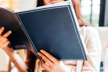Woman seeing inside blue cover menu and considering for making order.