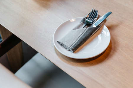 Cutlery set including spoon, fork, knife and napkin in white plate on wooden table.の写真素材