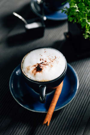 Hot cappuccino with cinnamon served in blue cup.の写真素材