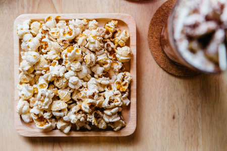 Top view of Salted popcorn served in square wooden plate on wooden table.の写真素材