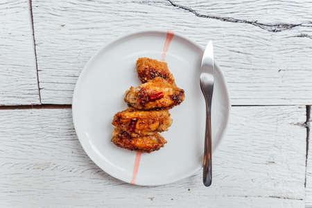 Korean Chicken Wings stir with Korean style sauce served in white plate.