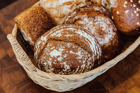 Freshly and warm baked bread rolls in the basket on wooden table. Made by artisan.の写真素材