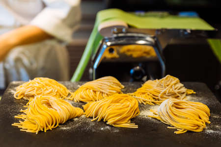 Homemade piles of fresh egg spaghetti pasta that powdering flour to keep them from sticking.の写真素材