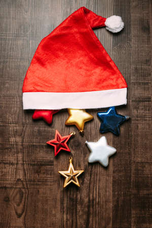 Santa hat with metallic stars on wooden background. Flat lay for Christmas and happy new year banner