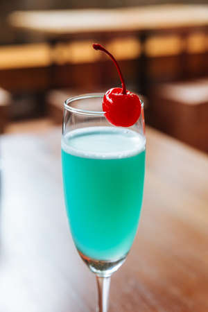 Turquoise color cocktail served with fresh cherry.の写真素材