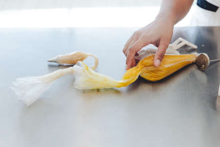 Hand on pastry bags with colored cream inside for making decorated flower for cake.の写真素材