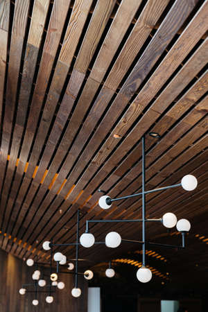 Retro light bulb lamps hang from dark oak wooden ceiling. Warm, cozy and elegant design.の写真素材