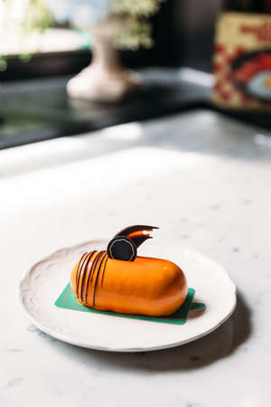 Classic Thai Tea Mousses Cake decorated with chocolate in white plate on marble top table.の写真素材