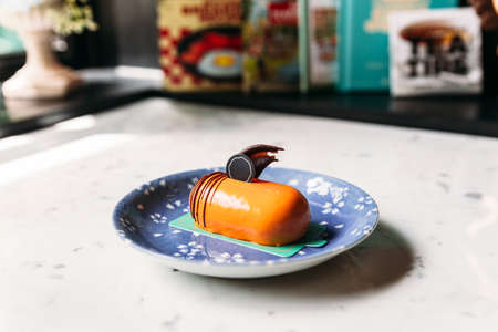Classic Thai Tea Mousses Cake decorated with chocolate in blue plate on marble top table.