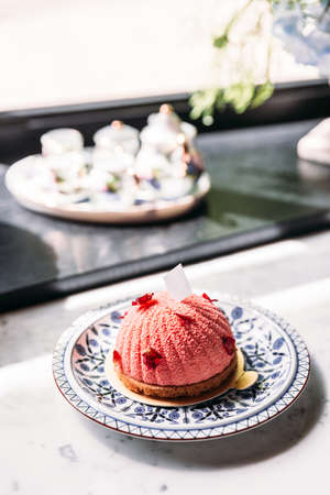 Rose and Lychee Mousses Cake decorated with rose petals in blue and white porcelain plate on marble top table.の写真素材