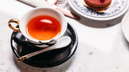 Hot Apple Tea served in porcelain vintagr cup with mousses cake on marble top table.