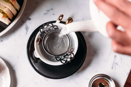 Hot Butterfly Pea Blueberry Tea served by pouring from mug through stainless steel tea strainer...