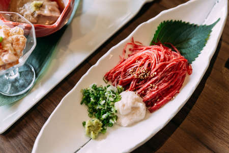 Raw Wagyu beef sliced in line like noodle served with minced scallion and daikon and topping with sesame.の写真素材