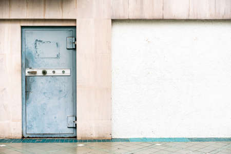 Old steel door with safety lock on the left side with white and brown stone wall. Perfect for background.の写真素材