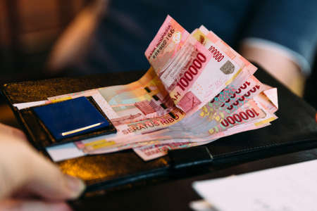 Man is paying in cash with Indonesian banknotes. Indonesian currency banknotes payment method.の写真素材