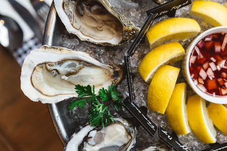 Close up Top view of Fine de Claire Oyster and Many kinds of Fresh Oysters served in round tray with slice lemon and spicy sauce.の写真素材
