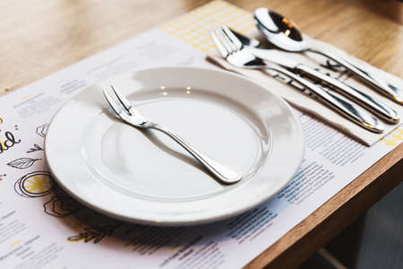 Oyster fork with cutlery: Spoon, Fork and Knife on white ceramic plate. Silver plated food ware.の写真素材