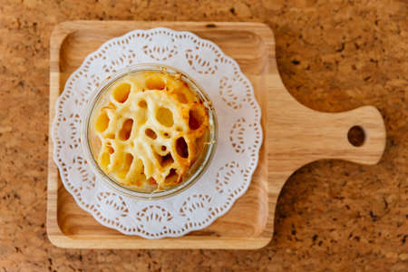 Top view of Cheese Baked Penne in glass bowl on wooden plate with salt, pepper and cutlery.