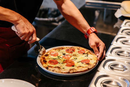 Chef slice a hot Caprese Bianca Pizza before serving. Ingredients are Mozzarella, Parmesan, Olive...