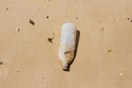 Top view of one time used plastic bottle on the sand beach in Koh Mak Island at Trat, Thailand. Save the world from plastic, background with copy space.の写真素材