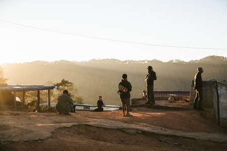 People are on the hill when the sun is going down at golden hour in the Akha village of Maejantai on...