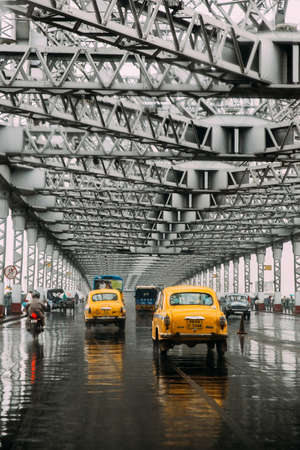 Yellow taxis running on the road inside Howrah Bridge in the afternoon with rain in Kolkata, India.のeditorial素材