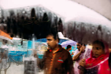 Indian people walking in the rain with umbrella, view through car's window with rain drops and stream near the area of Howrah Junction railway station at Kolkata, India.のeditorial素材