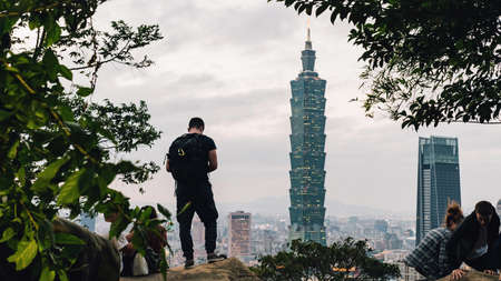 Tourist trekker taking a photo of Taipei 101 Skyscraper from Xiangshan Elephant Mountain in the evening in Taipei, Taiwan.のeditorial素材