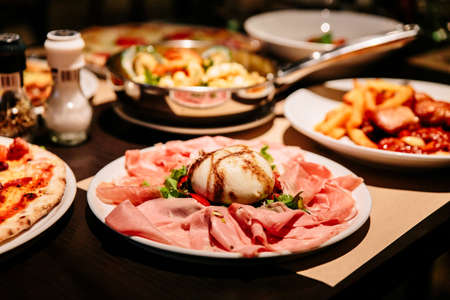 Cold Cuts Burratina: Burrata Cheese served with Parma Ham, Mortadella and Salad. Served in white plate on paper mat.の写真素材