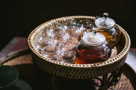 Hot Chamomile Tea in glass tea pot with empty glasses in basket for testers in the Akha village of Maejantai on the hill in Chiang Mai, Thailand.の写真素材