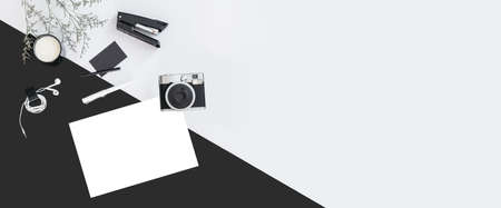 Black and white color background with flower branches, a cup of milk, earphone, pen, stapler, camera, name card and white paper. Architect and designer background with copy space.の写真素材