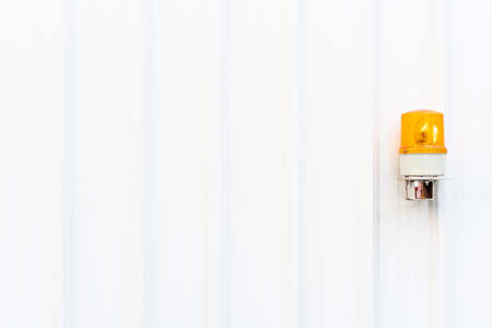 White corrugated metal wall texture with yellow emergency light on the right side