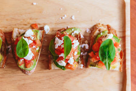 Top view of Avocado Toast with Cherry Tomatoes and Feta Cheese, Topping with Rocket leaves.