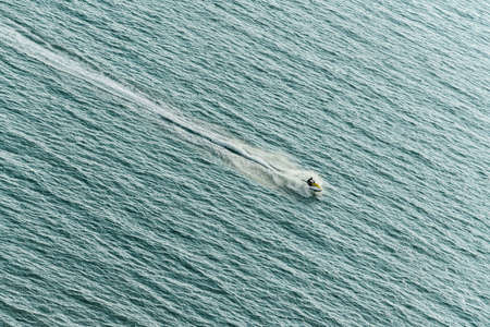 Man ridding jet ski on the sea with splashing water trace on the sea surface.の写真素材