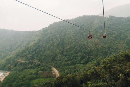 Gondola lifts moving over mountain with green trees in the area of Sun Moon Lake Ropeway in Yuchi Township, Nantou County, Taiwan.のeditorial素材